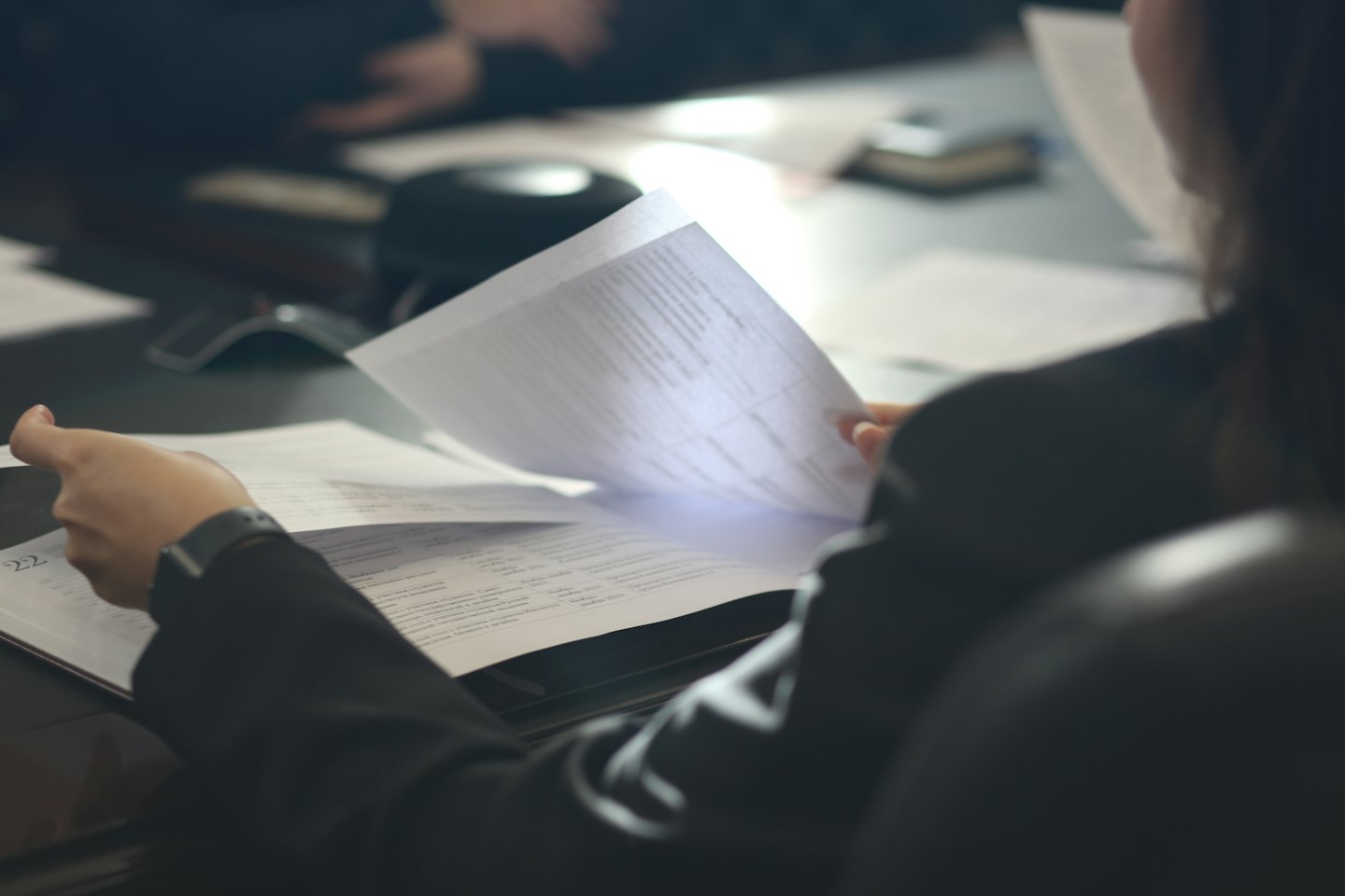 Person in suit turning pages in a business binder.