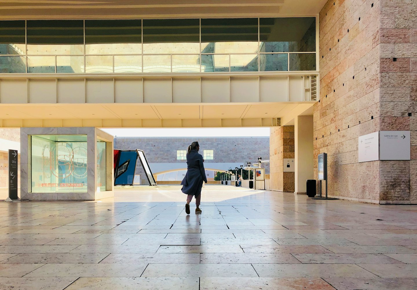 Person walking down a modern hallway with stone walls and floor.