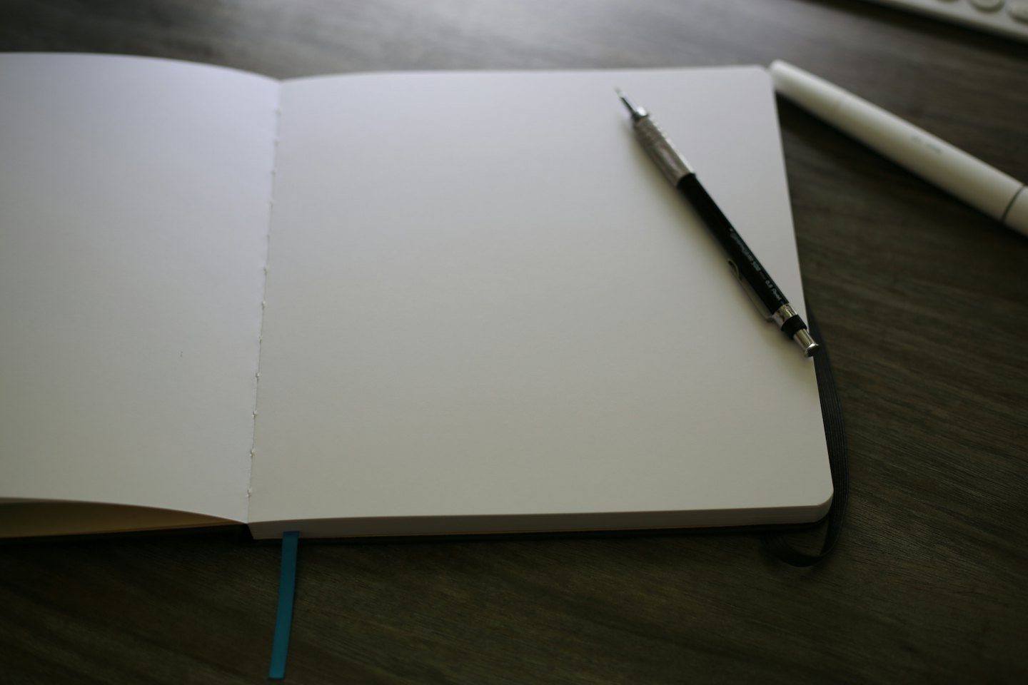 A blank notebook with a pencil on a wooden desk.